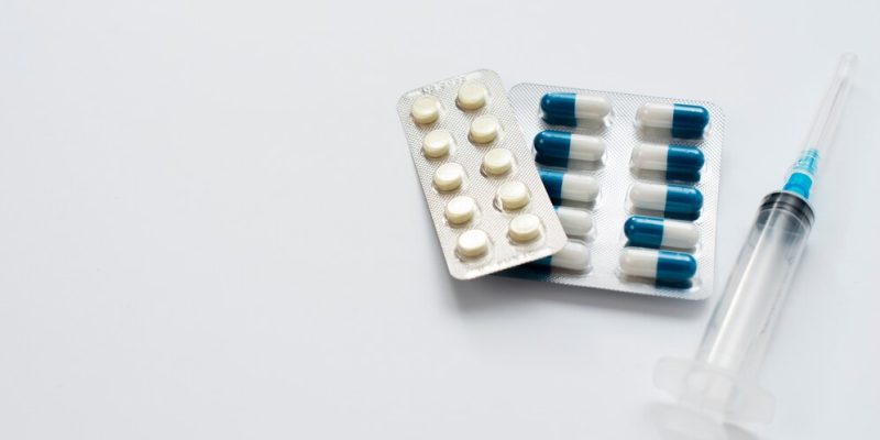 Imagem de cartelas de remédios e seringa.