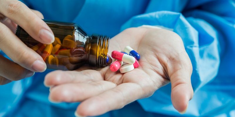 Imagem de médico derrubando medicamento sobre a mão.
