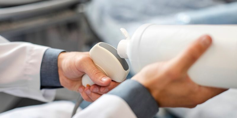 Imagem de médico aplicando gel em equipamento de ultrassonografia.